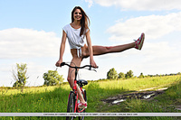 Cheyanna cheyanna strips outdoors as she rides her bike.